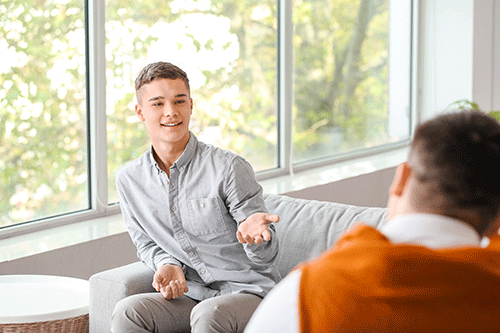 a teen gestures and smiles toward a therapist