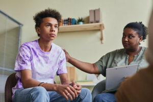 an adolescent boy is comforted by a therapist in an adolescent anger management 