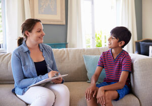 a boy talks with a therapist in a psychotherapy program