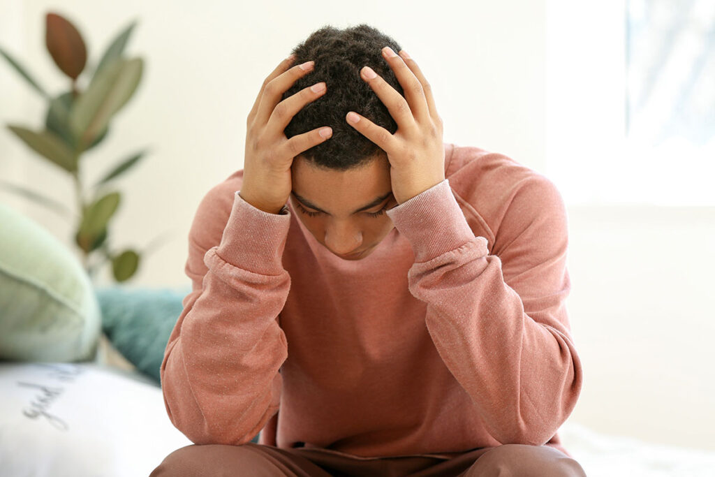 teen struggling with their mental health holds their head after researching what is cutting