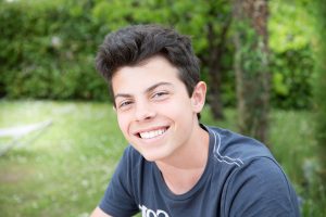a teen boy smiles after learning about the signs of autism