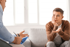 a young boy listens to a therapist during adolescent therapy 