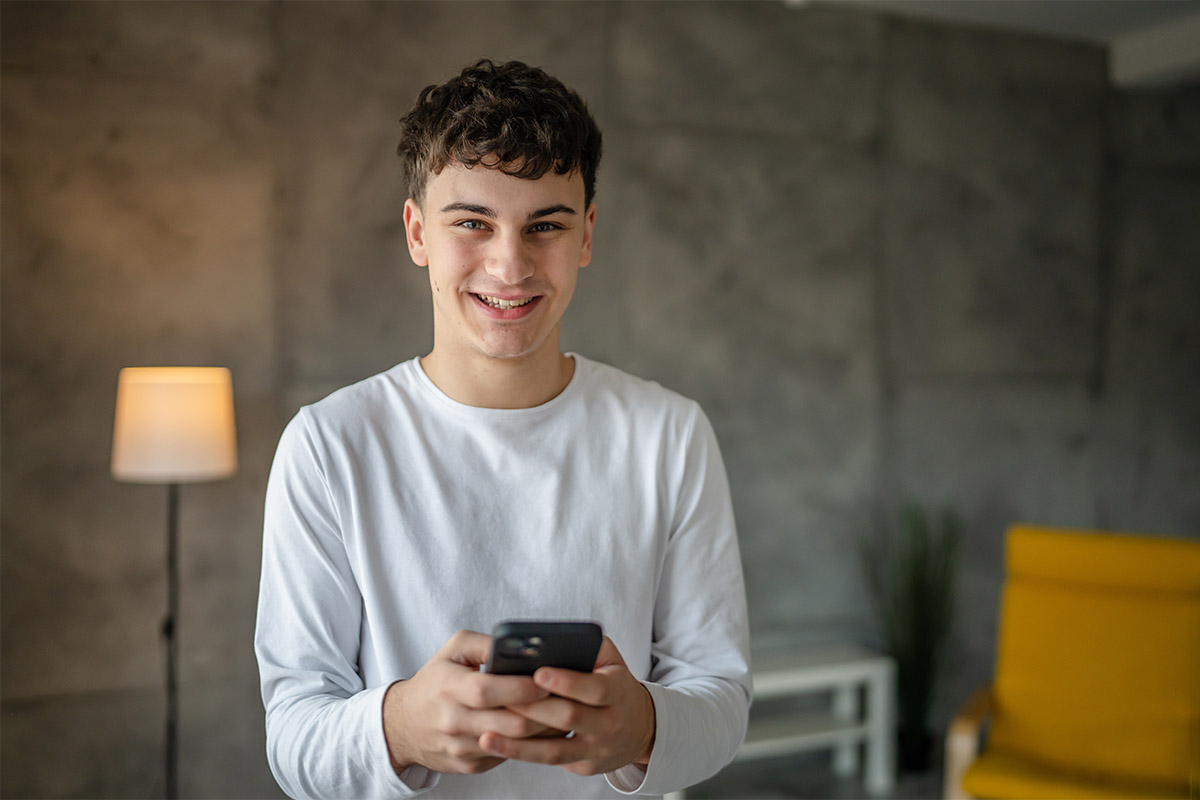 a teen smiles as he uses his phone to research "adhd and impulse control"