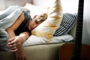 a teen lies in bed thinking of practicing meditation for sleep and anxiety