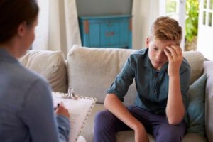 a teen talks to a therapist in an anger management program