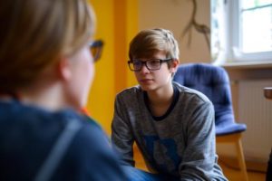 a teen listens to a therapist during adolescent bipolar disorder treatment