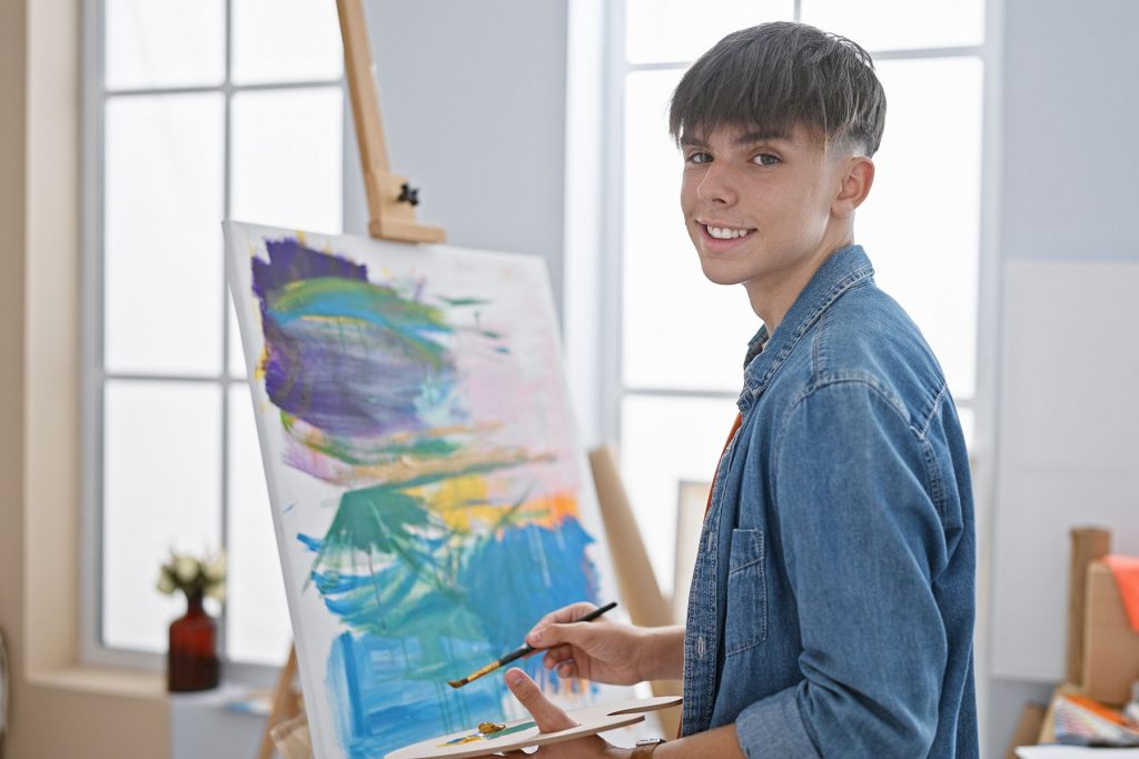 a teen smiles as he paints, realizing that it can help his mental health