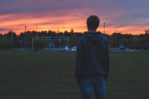 a teen looks at a school at sunset after dealing with school stress