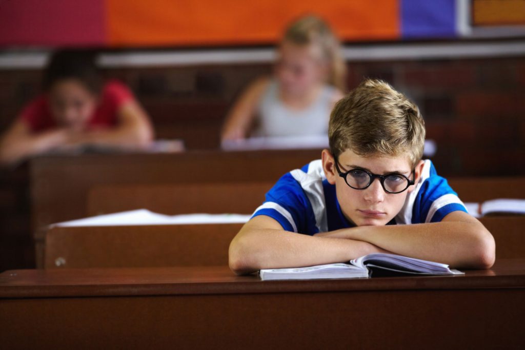 a teen sits in class looking bored, needing tips to manage adhd as a teen