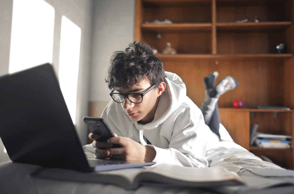 a teen uses a phone and laptop, raising concerns about the connection between technology and adhd in teens