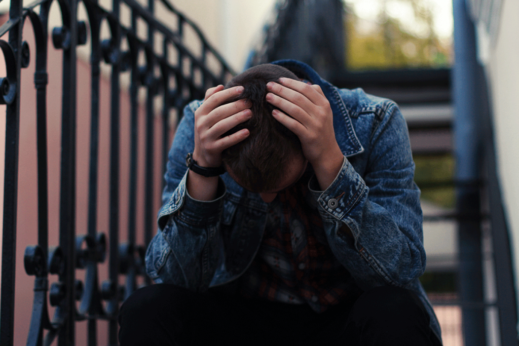 a teen holds their head wondering what is adolescent bipolar disorder