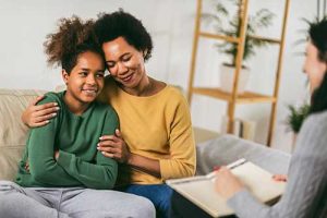 a teen and parent embrace in front of a therapist during adolescent residential treatment