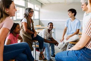 a group of teens talk with a therapist about the benefits of group therapy