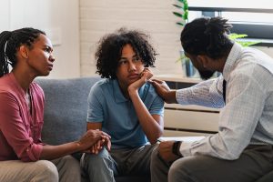 a parent and therapist comfort a teen during childhood trauma treatment 