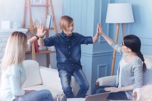a teen, parent, and therapist high five during disruptive mood dysregulation disorder treatment 