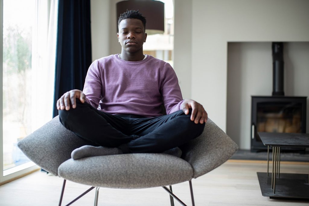 a teen practices somatic therapy exercises by meditating in a chair