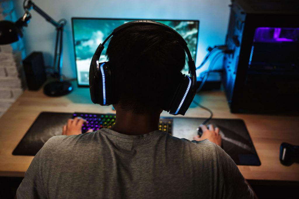 a teen with a video game addiction sits at a computer gaming
