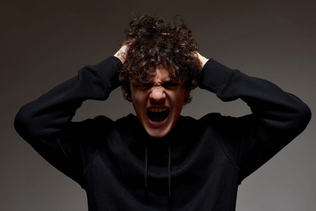 a teen screams as he experiences anger and puberty