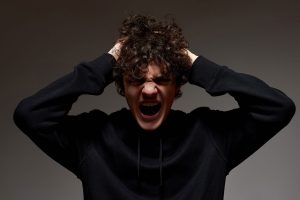 a teen screams as he experiences anger and puberty