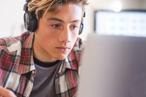 a teen uses his computer, maybe for gaming, social media or other typical teenage behaviors