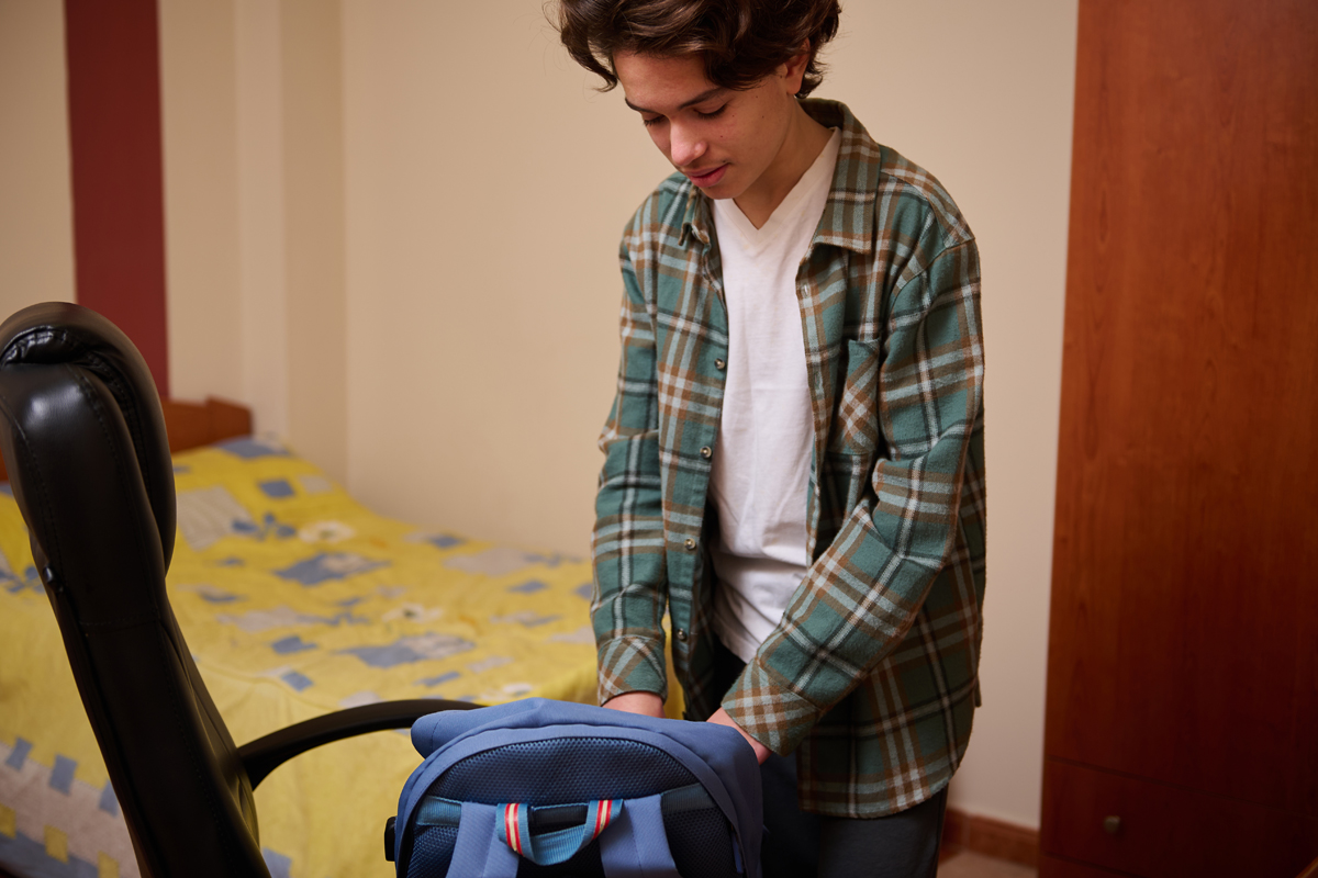 Teen boy packing backpack